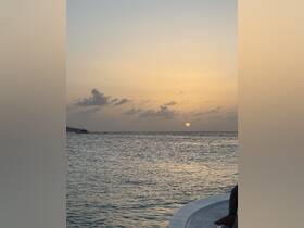 A serene sunset view over the water with a boat in the distance, capturing the tranquil beauty of evening on the sea.