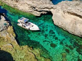 A stunning aerial view of a boat navigating through crystal-clear waters, surrounded by rocky cliffs — perfect for exploring hidden coves and enjoying serene aquatic landscapes.