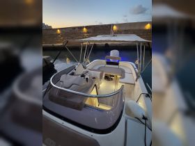 A well-lit interior view of a boat's helm and seating area, showcasing the modern design and amenities perfect for a comfortable day on the water.