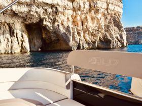 A serene view of a boat's interior with a stunning rocky cliff backdrop, perfect for exploring coastal caves and enjoying the tranquility of the water.