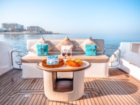 A beautifully arranged table on a yacht featuring refreshments and comfortable seating, perfect for enjoying a relaxing day on the water.