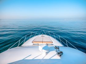 A stunning view from the front of a yacht, gliding over calm waters under a clear blue sky — perfect for serene boating experiences.