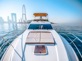 A stunning view of a yacht from the front, showcasing its sleek design against a backdrop of a city skyline and a ferris wheel, perfect for luxury outings on the water.