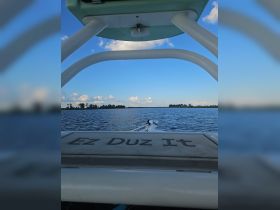 A view from the helm of a boat named 'Ez Duz It,' cruising on calm waters under a clear blue sky, showcasing the serene boating experience.