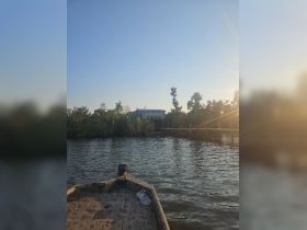 A scenic view from the front of a boat, showcasing a tranquil waterway and a house along the shore, perfect for exploring the natural beauty of the area.