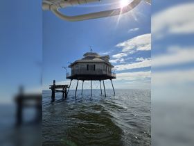 A unique structure stands above the water, but the image lacks clarity and focus, making it difficult to identify specific details.