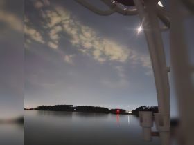 A nighttime view of a calm water scene with clouds and distant lights, but the image lacks clarity and focus.