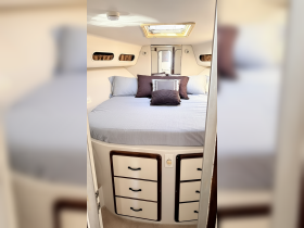 Cozy cabin interior featuring a comfortable bed with decorative pillows, perfect for relaxing on a boat getaway.