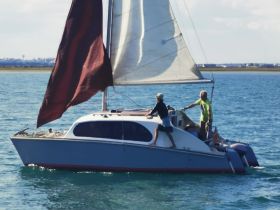 Two individuals navigate a catamaran under sail, showcasing the thrill of sailing on open waters — a perfect adventure for sailing enthusiasts.