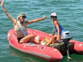 Two women enjoy a fun moment on an inflatable boat, showcasing the joy of summer adventures on the water.