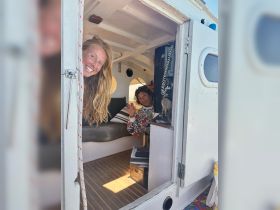 Two women smile from inside the cozy cabin of a boat, showcasing the inviting interior space perfect for relaxation and socializing.