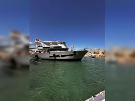 A sleek yacht named 'Primus' docked in clear waters, showcasing its modern design against a vibrant blue sky — perfect for luxury charters and coastal adventures.