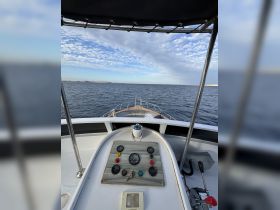 A view of the helm and control console from inside the boat, showcasing the essential navigation instruments and a glimpse of the water ahead.