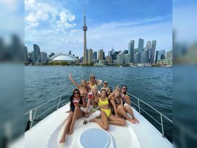 A lively group of friends enjoys a boat party in Toronto, celebrating against the stunning city skyline with drinks in hand.