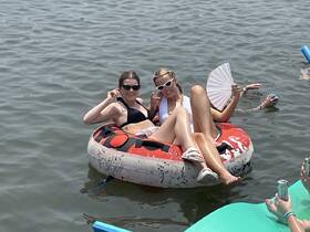 Two friends enjoy a sunny day on a floating tube, surrounded by water and laughter — a perfect scene for summer fun and relaxation.