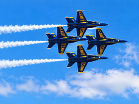 A formation of U.S. Navy jets performing an aerial display against a clear blue sky.