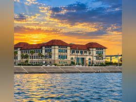 A stunning sunset casts vibrant colors over a waterfront building, creating a picturesque scene perfect for evening strolls along the water.