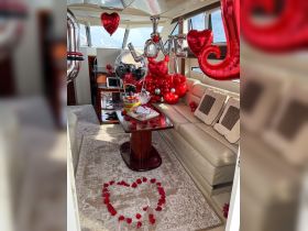 A beautifully decorated interior of a boat featuring romantic elements like balloons, rose petals, and a cake, perfect for special celebrations or intimate gatherings.