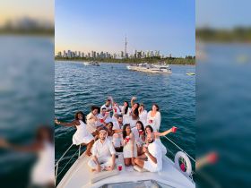 A vibrant group celebrates aboard a yacht, enjoying drinks and the stunning skyline of Toronto — perfect for unforgettable summer parties on the water.