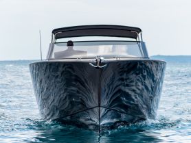 A sleek yacht is captured from the front as it glides through the water, showcasing its elegant design and smooth movement.