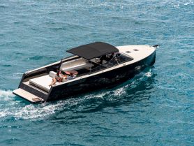 A couple enjoys a sunny day aboard a stylish boat, cruising through vibrant turquoise waters — perfect for romantic getaways or leisurely outings.