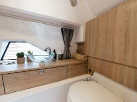 A stylish interior view of a boat's bathroom area featuring a modern sink and wooden accents, perfect for a comfortable boating experience.
