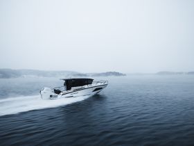 A sleek speedboat glides through calm waters, showcasing its dynamic design and performance in a serene, misty environment.