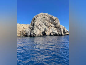 A stunning view of a rocky coastline with a boat visible nearby, showcasing the natural beauty of the area — perfect for sightseeing and exploration.