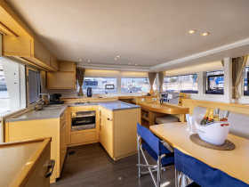A modern and spacious interior of a yacht featuring a well-equipped kitchen and comfortable seating area, perfect for relaxing and dining while on the water.