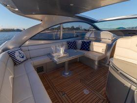 A stylish interior view of a boat's lounge area, featuring comfortable seating and a polished table, perfect for relaxing on the water.