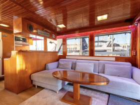 Cozy interior of a boat featuring a comfortable lounge area with a stylish table and large windows, perfect for relaxing while enjoying the views.