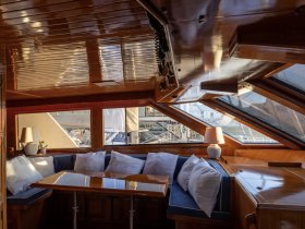 Cozy interior of a boat featuring a comfortable seating area with plush cushions and a polished table, perfect for relaxing or dining while enjoying the views.