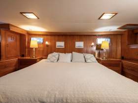 Cozy and elegantly designed cabin interior featuring a spacious bed, warm wood finishes, and ambient lighting — perfect for restful nights on the water.