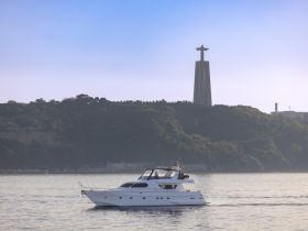 A sleek yacht cruises through calm waters with the iconic Christ the Redeemer statue in the background, showcasing a perfect blend of maritime beauty and cultural landmarks.