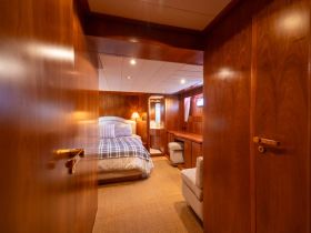 A cozy and elegantly designed cabin interior featuring a comfortable bed and seating area, perfect for relaxing on a yacht.