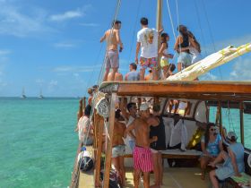 A lively group enjoys a sailing adventure on a boat, soaking up the sun and ocean views — perfect for a fun day out on the water.
