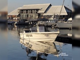 A serene view of the 'Hooked Again' boat docked at a marina, reflecting beautifully in the calm waters — perfect for fishing trips or leisurely outings.