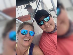 A joyful moment captured on a boat with a smiling woman and a young boy, showcasing the fun and connection of family outings on the water.