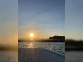 A serene sunset view from the bow of a boat, showcasing the tranquil waters and distant shoreline — perfect for evening cruises and relaxation on the water.