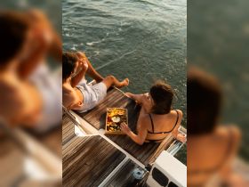 A couple enjoys a delightful spread of fresh fruits and drinks while relaxing on the deck of a yacht, capturing the essence of a perfect day on the water.
