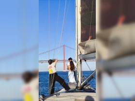 A couple enjoys a moment on a sailboat with a stunning bridge in the background, perfect for capturing special memories while sailing.