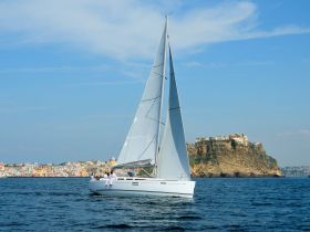 A beautiful sailboat glides through the water with guests on board, showcasing stunning coastal views — perfect for sailing adventures and exploring picturesque destinations.