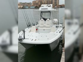 A sleek center console fishing boat docked, featuring multiple fishing rods and comfortable seating, perfect for a day on the water.