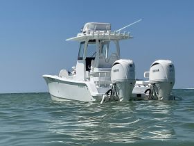 A sleek center console boat cruising through clear waters, showcasing its powerful Yamaha engines — perfect for fishing or leisure outings.