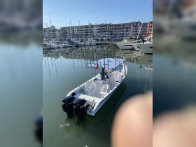 A center console fishing boat docked in a marina, showcasing its sleek design and fishing gear — perfect for a day out on the water.