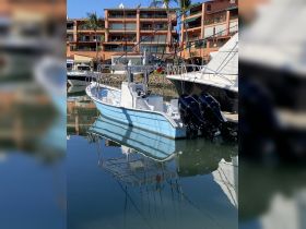 A picturesque view of a blue boat docked in a marina, reflecting beautifully on the calm water — ideal for fishing or leisure outings.