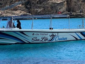 A scenic view of the 'Sea Life Cruises' boat with crew members onboard, set against a stunning turquoise backdrop — perfect for exploring coastal destinations.