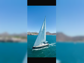 A stunning aerial view of a sailboat gracefully navigating through vibrant turquoise waters, showcasing the beauty of sailing adventures.