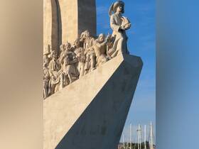 A close-up view of a monument featuring historical figures, showcasing intricate sculptures against a clear blue sky.