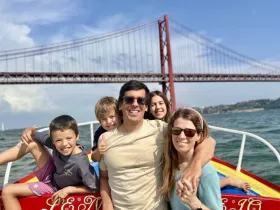 A joyful family poses together on a boat with a stunning bridge in the background, capturing a memorable day on the water.
